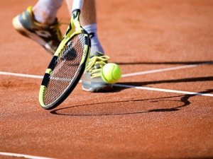 Player bouncing tennis ball with a racket