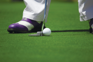 A person in white pants playing golf