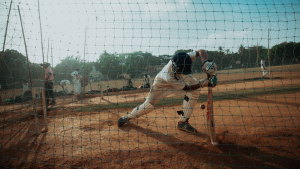 Cricket player in white uniform betting behind a net
