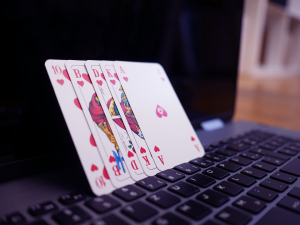 Close up of four face cards resting against a laptop screen and keyboard