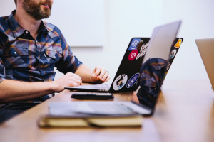 Person sitting at a table with three laptops on it