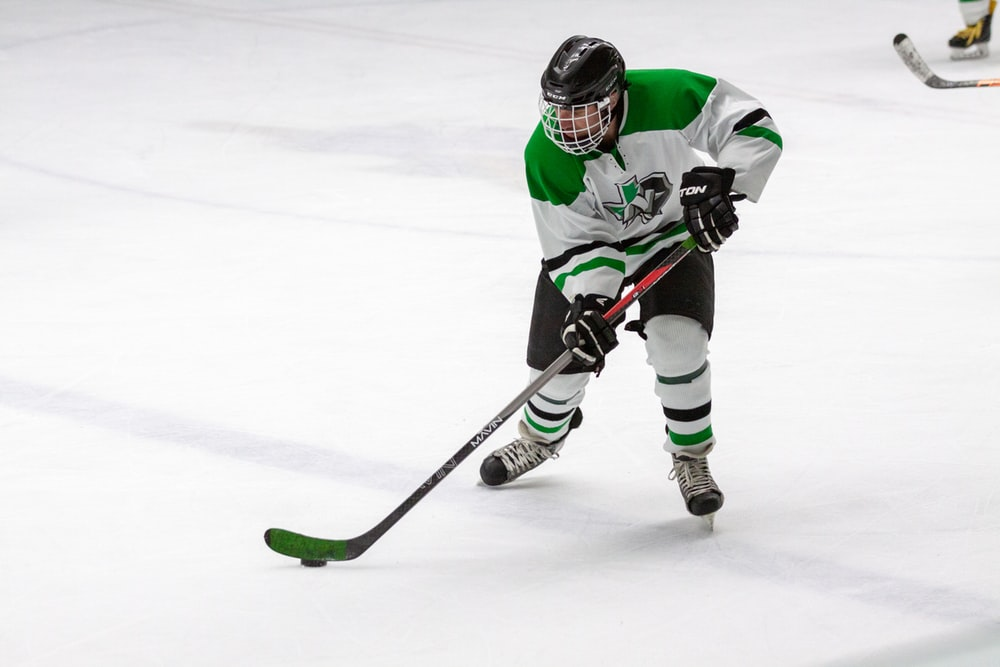 Player in white and green jersey playing ice hockey