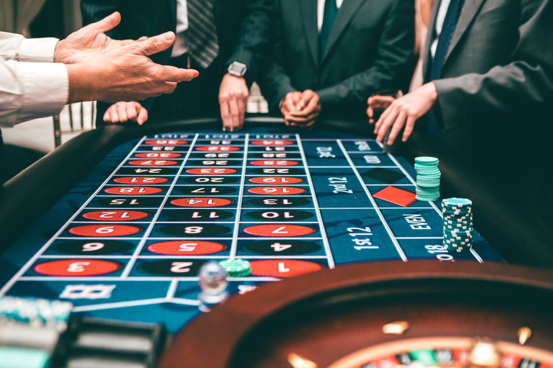 Cut-off shot of people in suits betting on games in a land-based casino