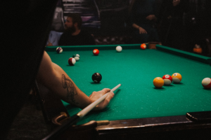 A snooker player leaning over to pocket balls with people sitting in the background