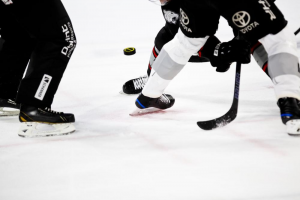 An ice hockey player swinging a shot