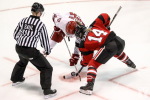 Two players playing ice hockey with the referee present