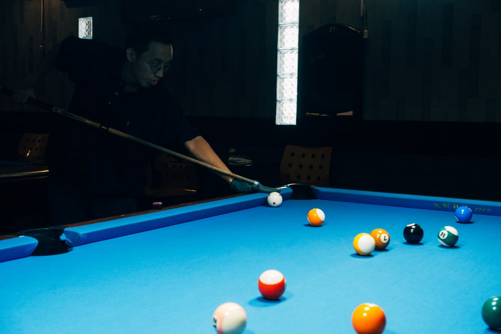 A man in a black shirt playing snooker