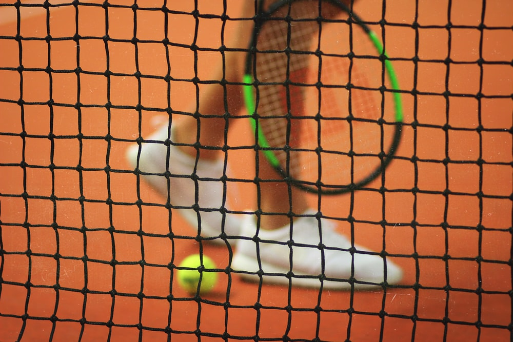 A tennis player holding a racket behind the net