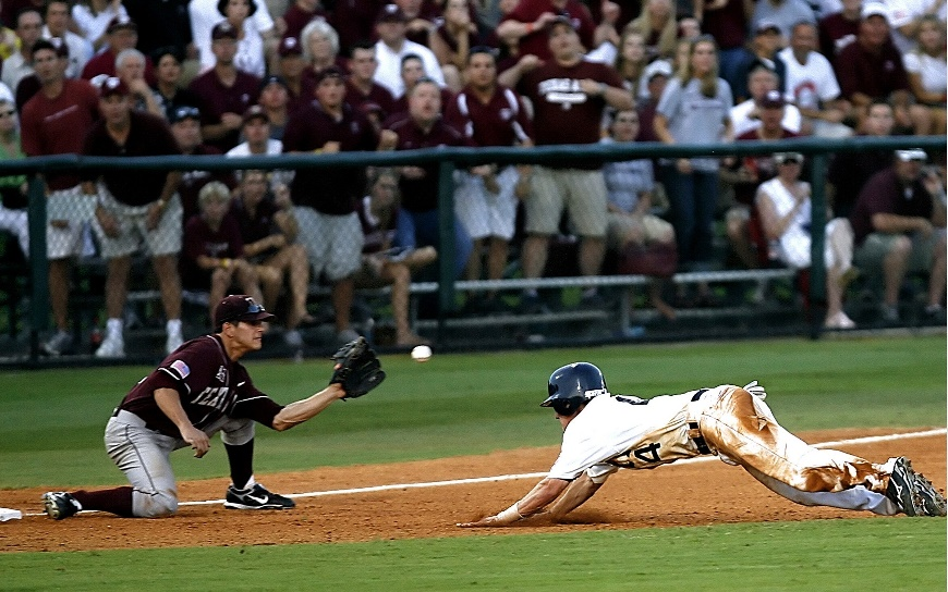 A player diving for the base while another catches the ball.