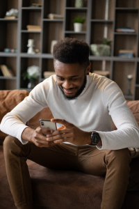 a man using smartphone while sitting on sofa