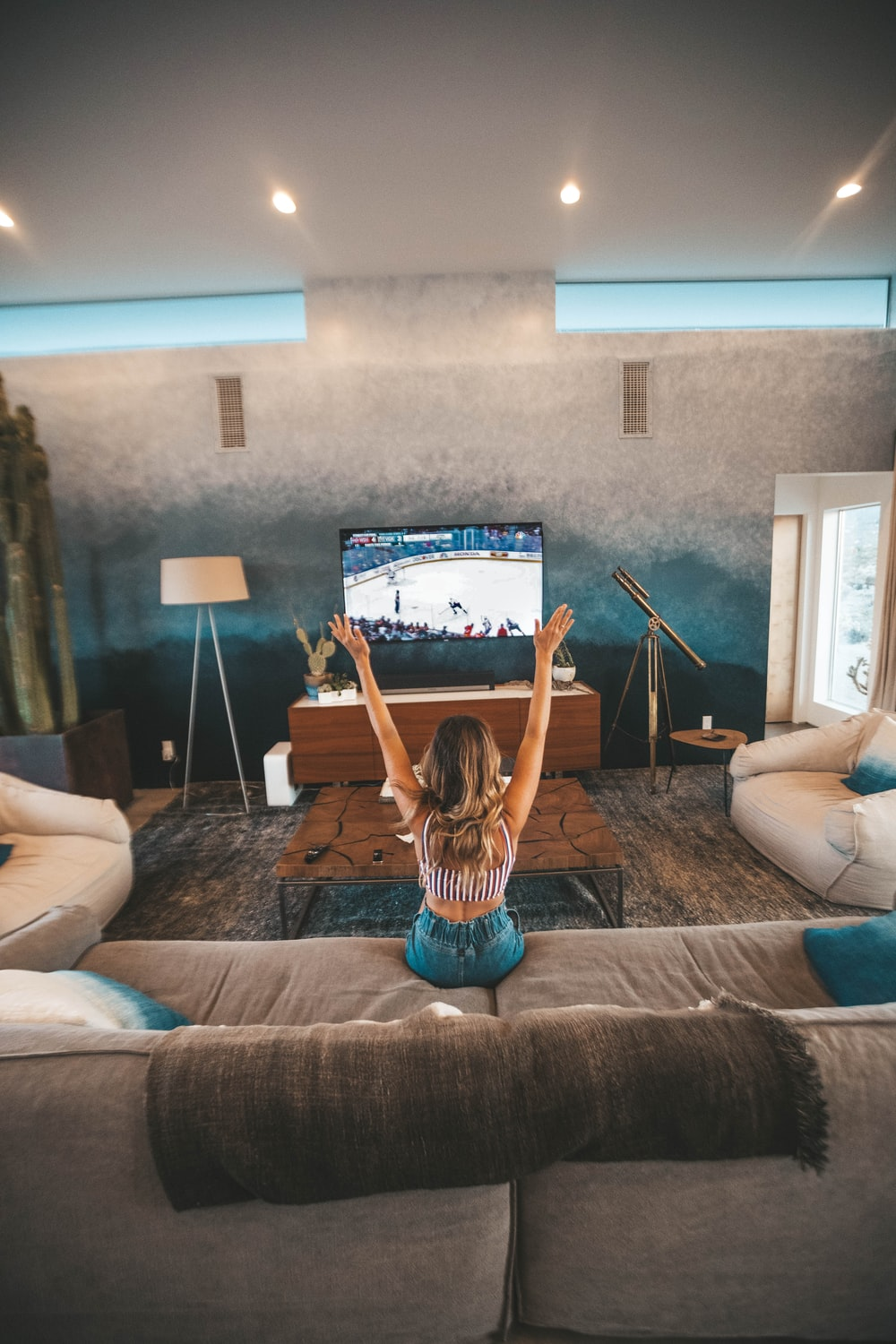 A woman throwing her arms up in celebration while watching an ice hockey game