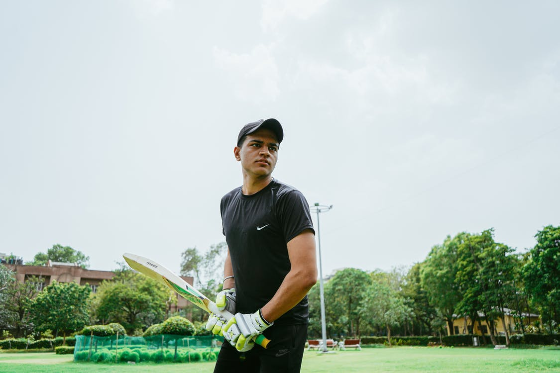 A man in sports gear posing with a cricket bat