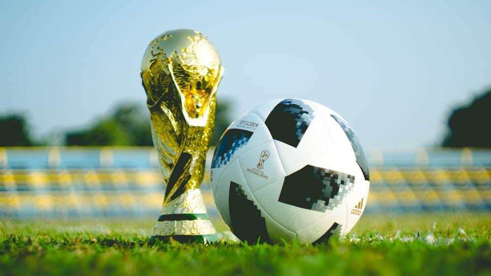 A FIFA World Cup trophy on the grass next to a football