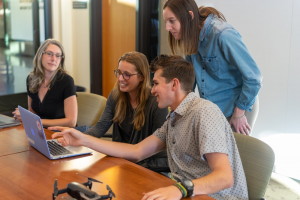 Four people happily discussing something on a laptop