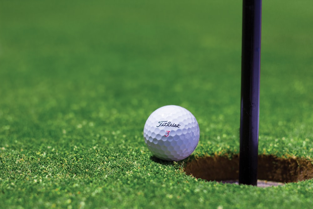 A golf ball sitting at the edge of a cup