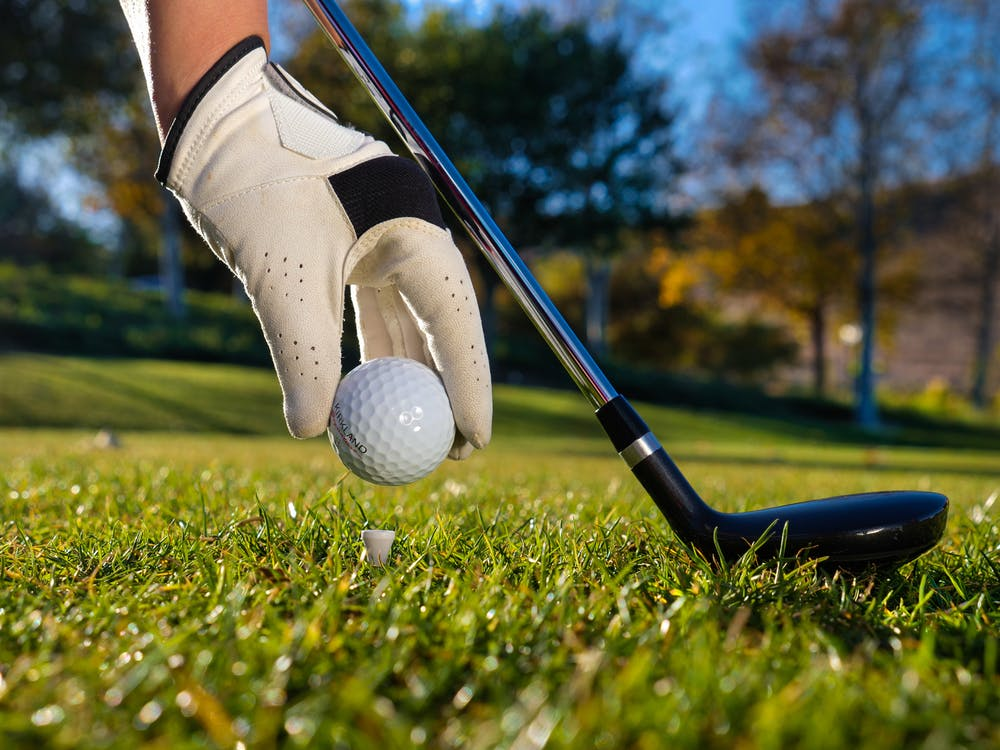 A golf player putting a golf ball on a tee while holding their club