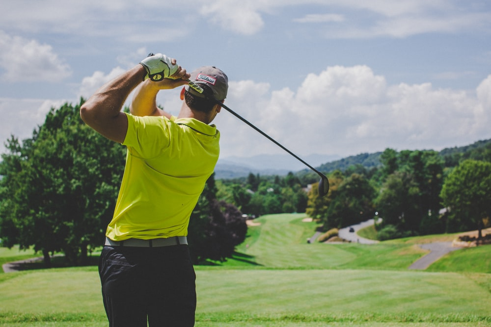 A golfer in a yellow shirt swinging his club