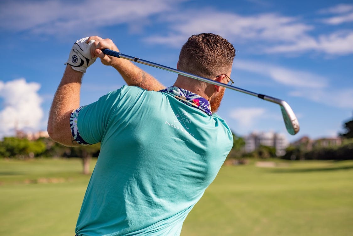A golfer in a blue shirt swinging his club
