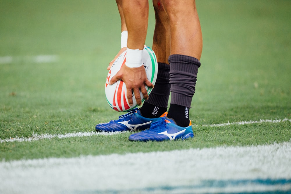 A rugby player putting a rugby ball on the field