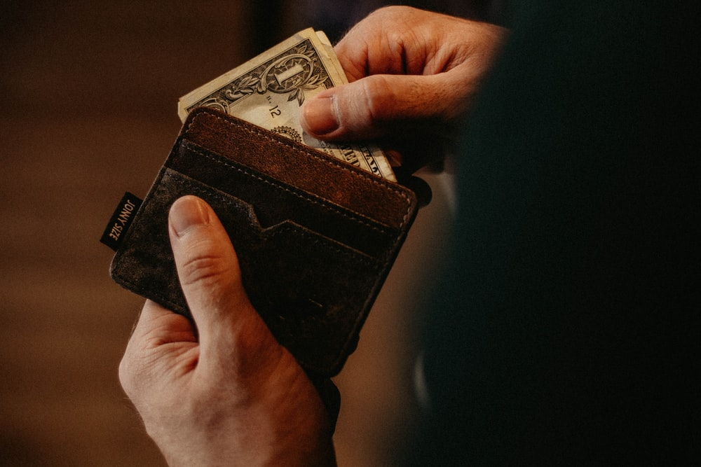 A person pulling folded cash out of a wallet