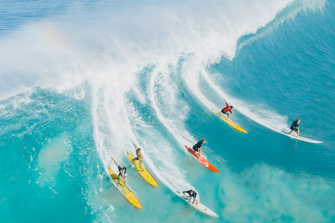 Six surfers riding a large wave