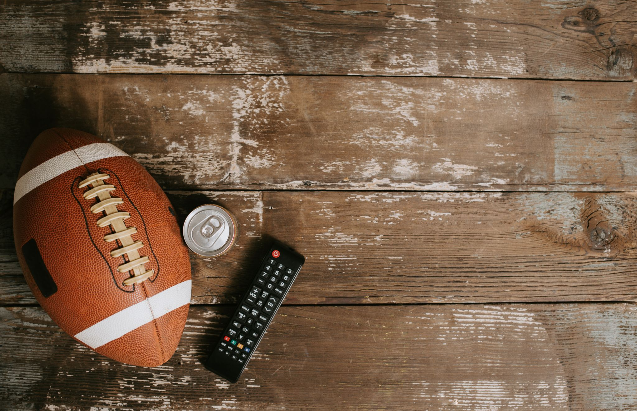 A football on a wooden table with a remote