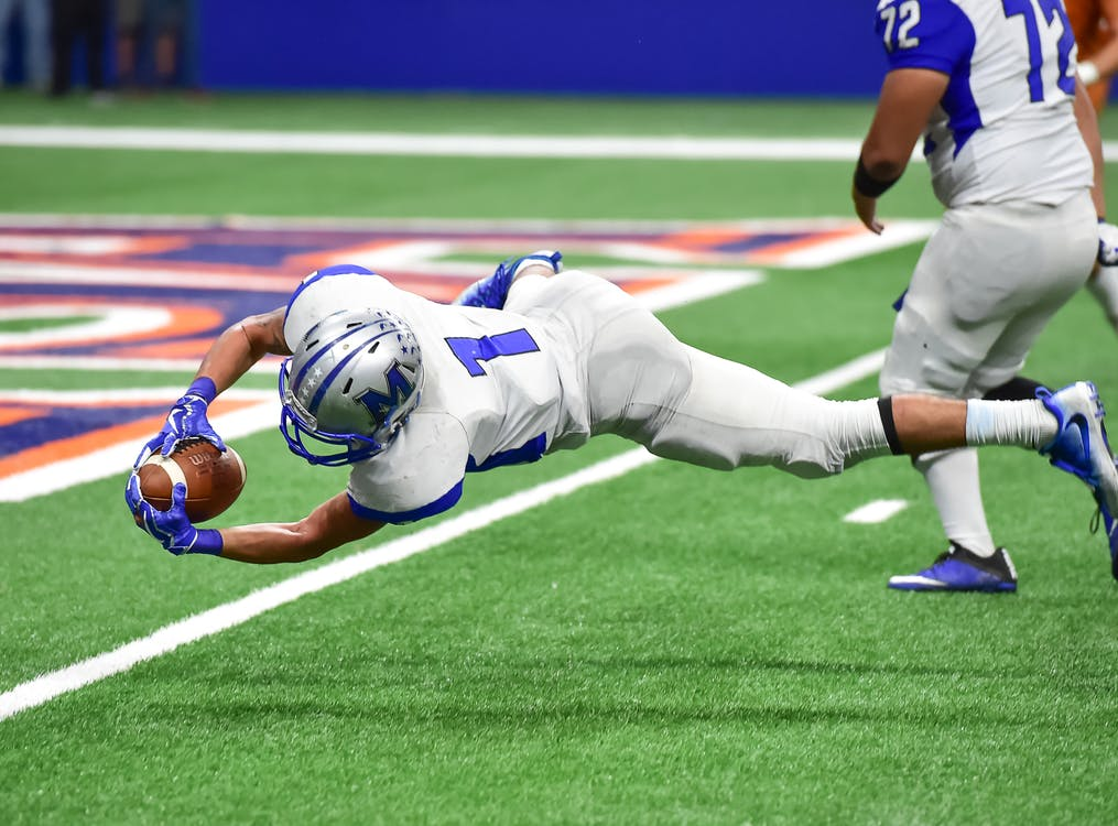 A football player falling while holding a football