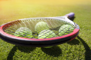 A tennis racket and balls on a grassy surface