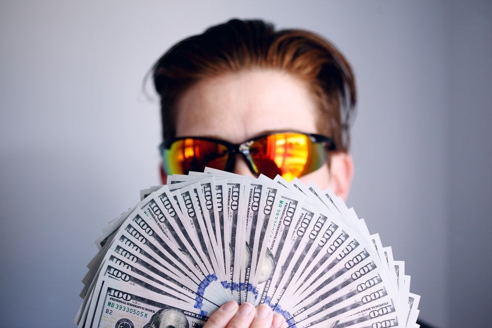 A person holding a set of hundred-dollar banknotes