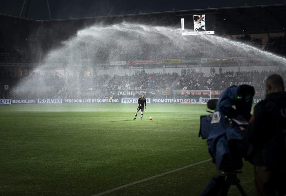 A soccer stadium being sprayed by a sprinkler