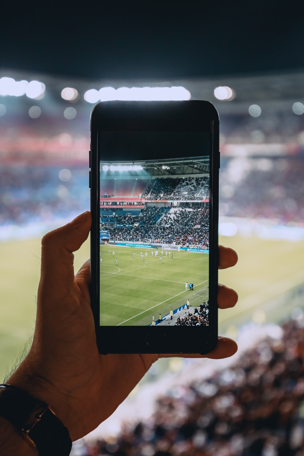 A bettor in the football stadium holding cellphone 