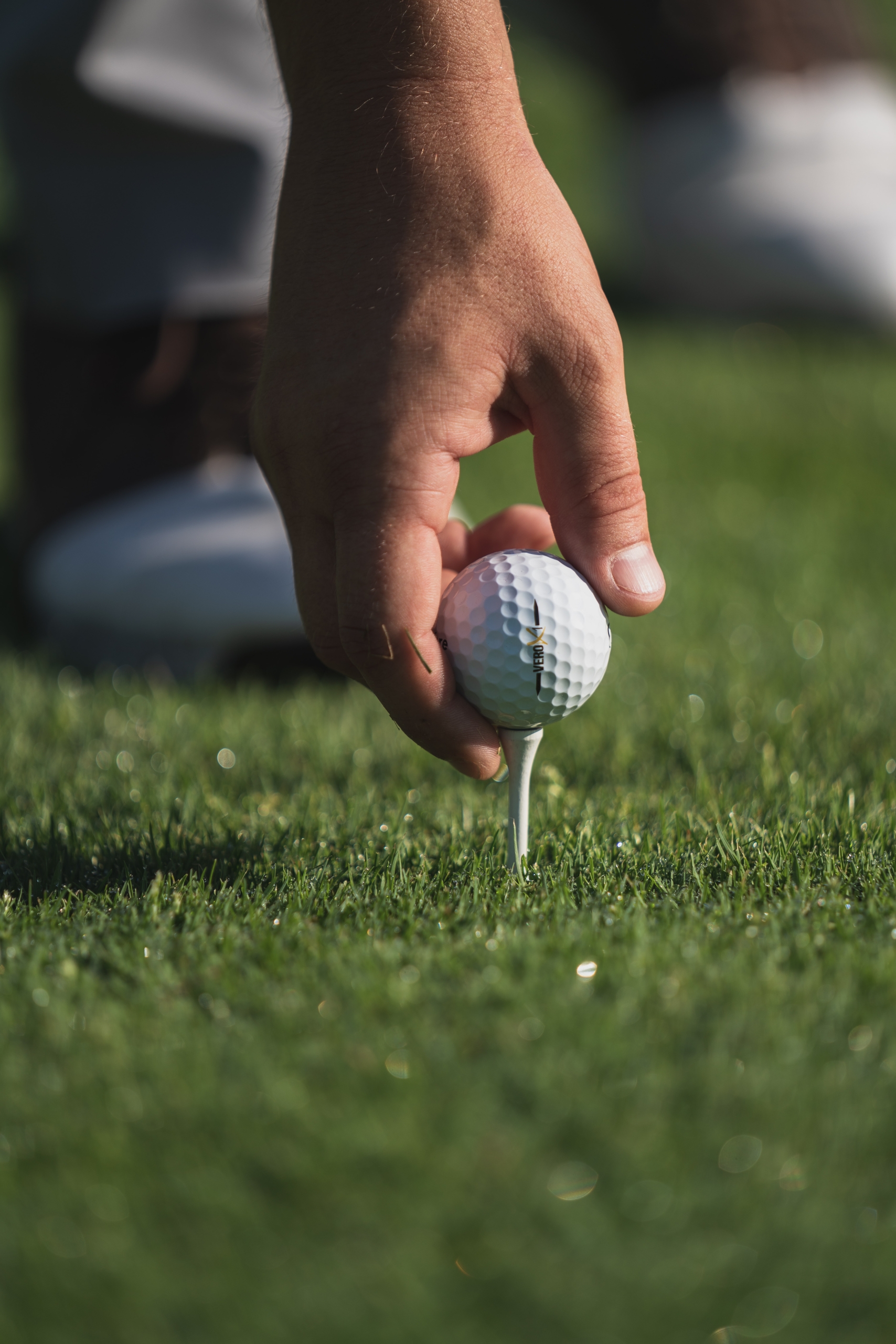 A person placing a golf ball on a tee