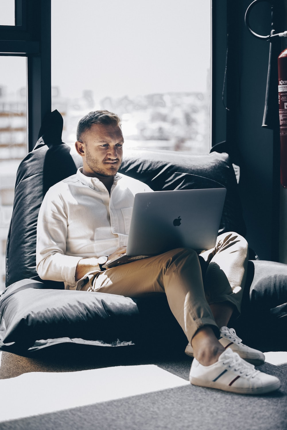 A man sitting on a bean bag using a laptop