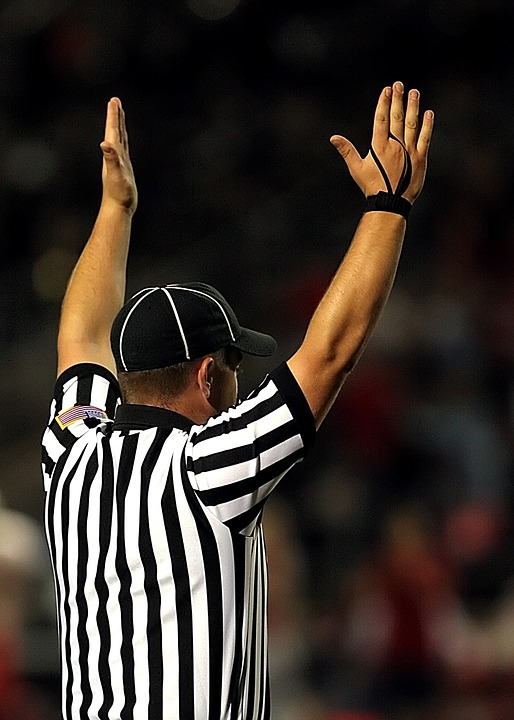 A football referee with his arms raised