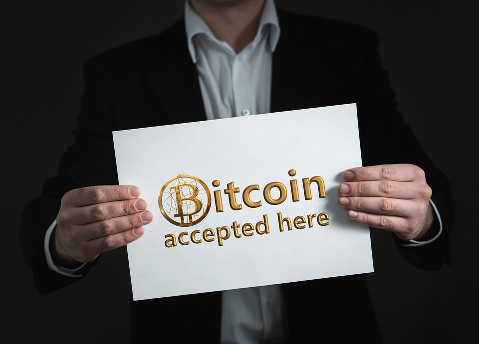 a person holding signage stating that they accept Bitcoin