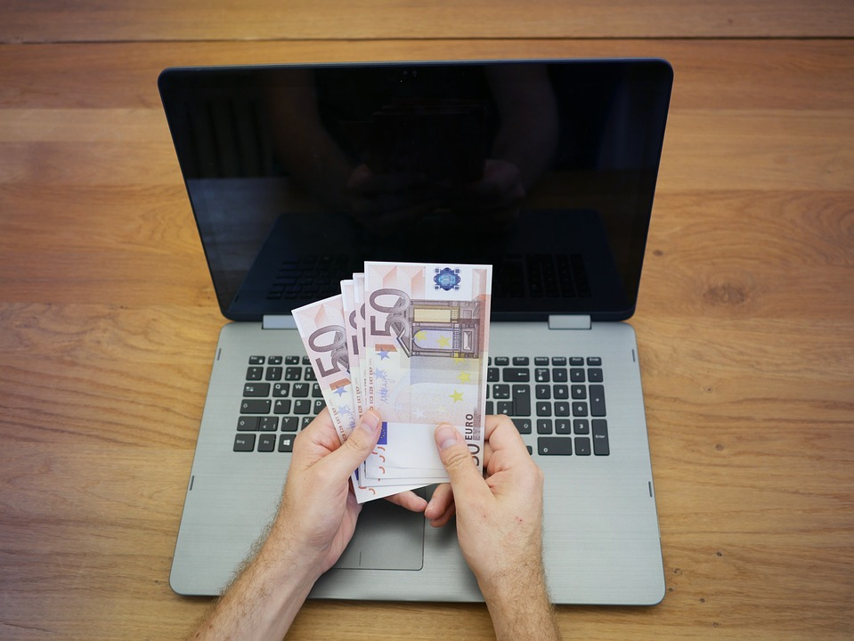 A person holding money in front of his laptop