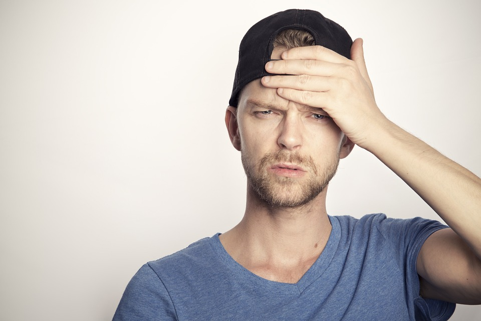 A person wearing a cap holding their head