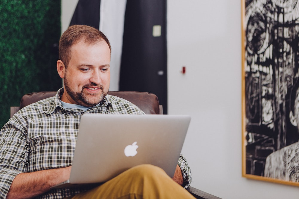 A man sitting on a chair using a laptop