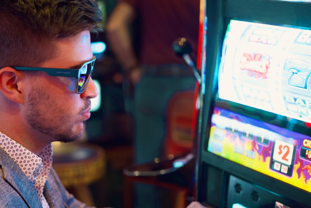 A man wearing sunglasses using a slot machine