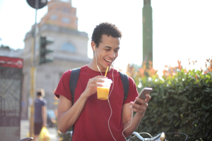 a man with a smartphone drinking juice on the street