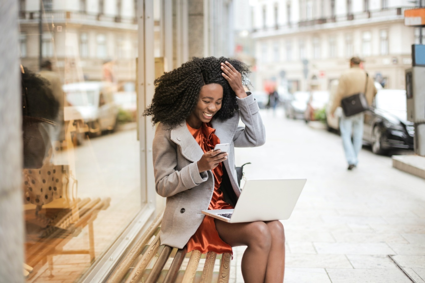 a woman in a gray coat sitting on a wooden bench