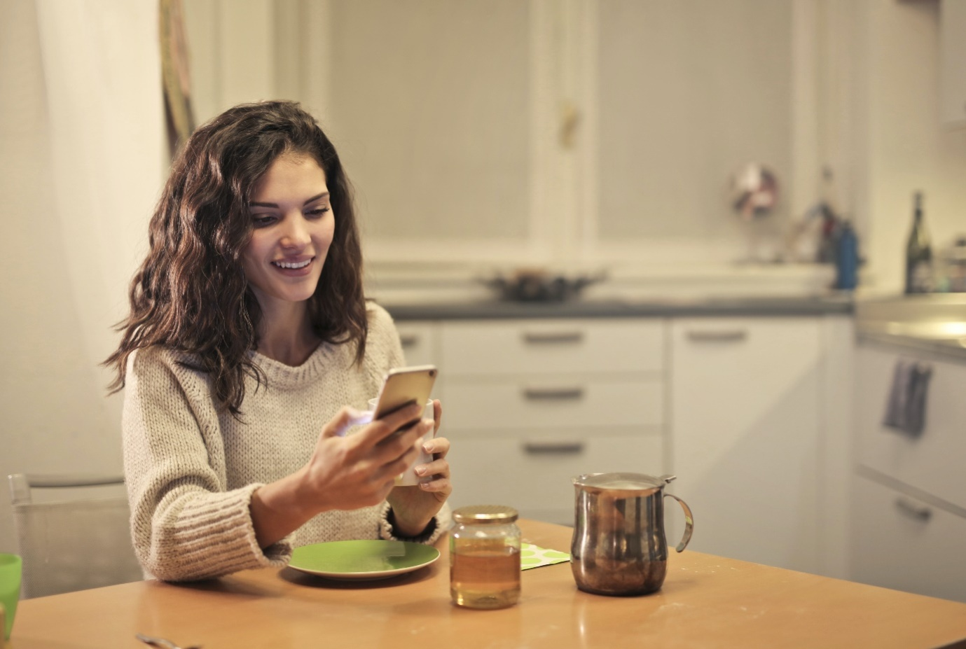 a young woman drinking tea and using a smartphone